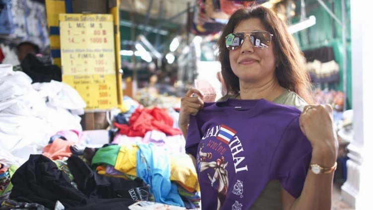 A lady choosing from a bunch of T-shirts to buy