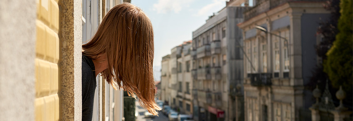A girl standing near window and looking road
