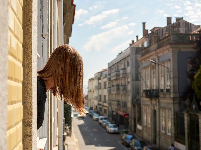 A girl standing near window and looking road