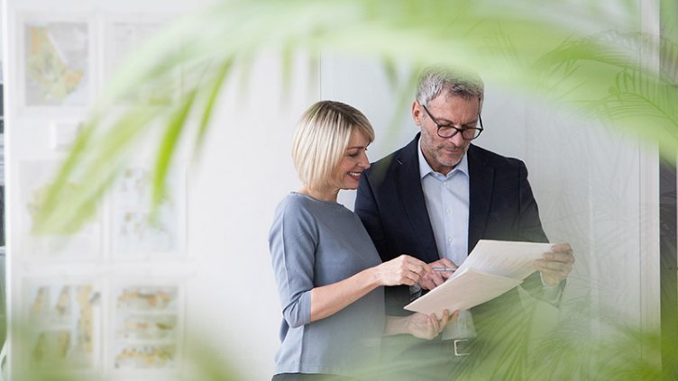 Businessman and woman working together in office discussing documents