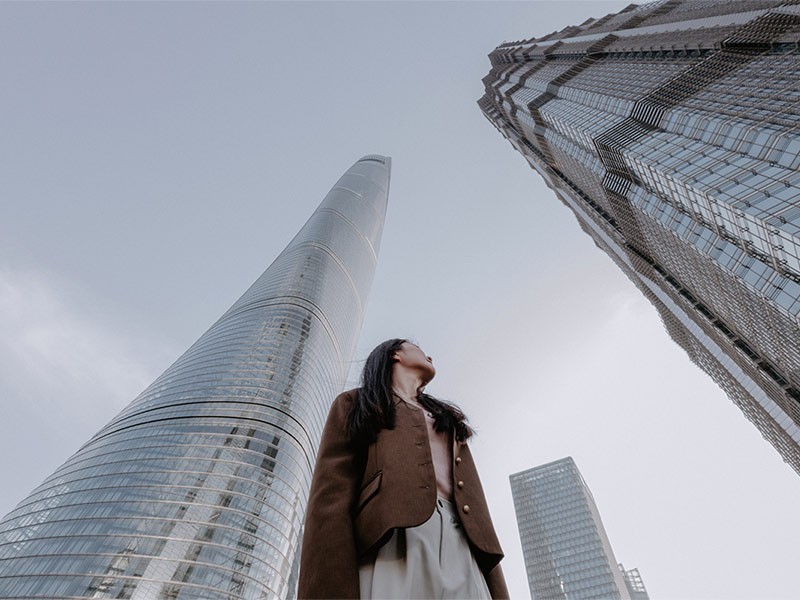 A girl standing and looking at high rise building