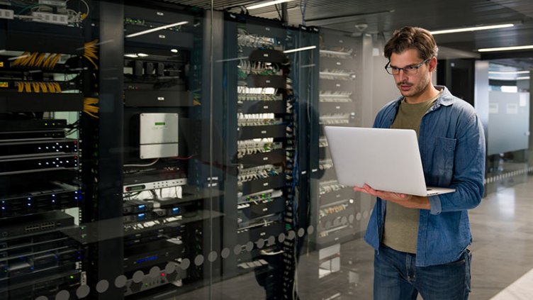 A person using laptop in a server room