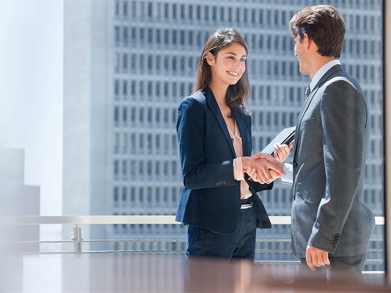 A female employee is shaking hand with male employee in office
